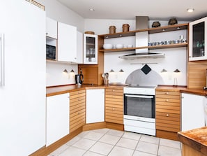A compact kitchen with white cabinets, a built-in oven, and wooden countertops.