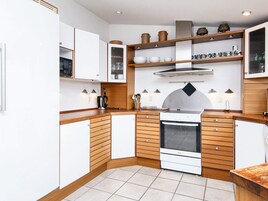 Una cocina compacta con armarios blancos, horno integrado y encimeras de madera.