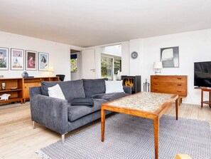 A modern living room with a grey sofa, a wooden coffee table, a TV, and a fireplace. - 6 Person Holiday Home in Borkop (Borkop)