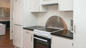 A compact kitchen with white cabinetry, a built-in oven, a stove, and a microwave. - Luxury Spa Retreat in Vejers - By Traum Ferienwohnungen (Vejers Strand)