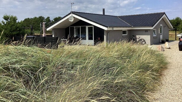 A small, single-story house with a sloped roof, a satellite dish, and a number '28' on the side. - Luxury Spa Retreat in Vejers - By Traum Ferienwohnungen (Vejers Strand)