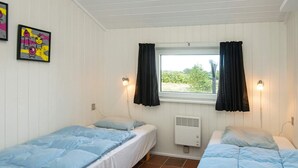 A room with two single beds, white walls, a window with black curtains, and a visible air conditioning unit. - Luxury Spa Retreat in Vejers - By Traum Ferienwohnungen (Vejers Strand)