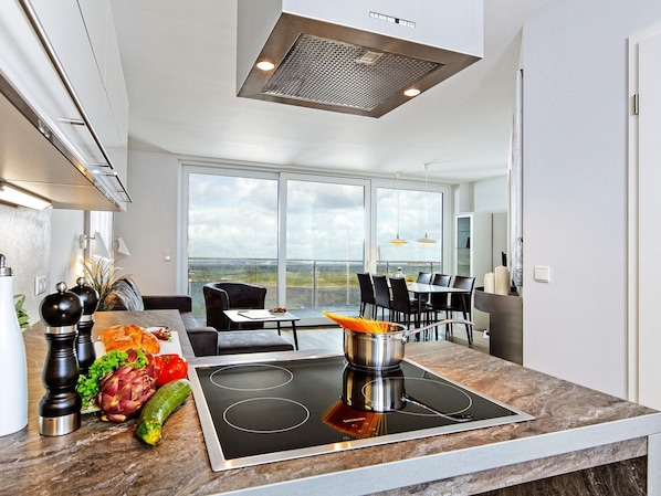 Una cocina moderna con estufa integrada, ventanas amplias y un comedor con vistas.