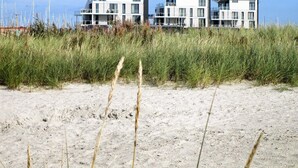 A beachfront property with modern architecture, featuring multiple balconies and a sandy foreground. - Holiday Home in Wendtorf (Wendtorf)