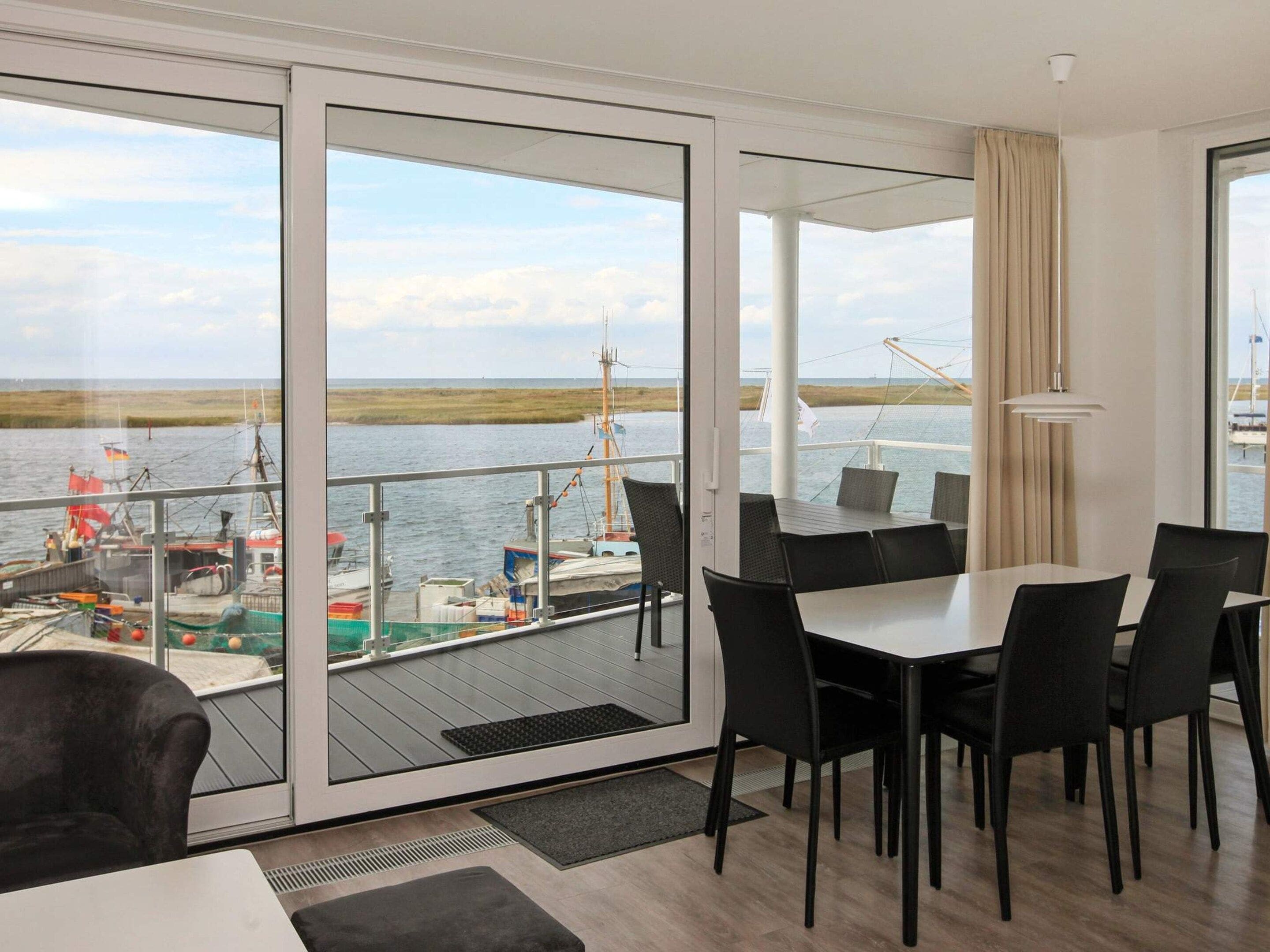 A modern room with a large sliding glass door leading to a balcony overlooking a body of water.