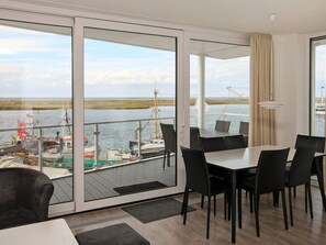 Una habitación moderna con un amplio ventanal corredero que da a un balcón con vistas a un cuerpo de agua.