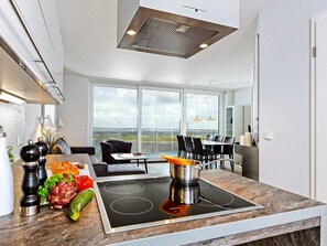 A modern kitchen with a built-in stove, large windows, and a dining area with a view.