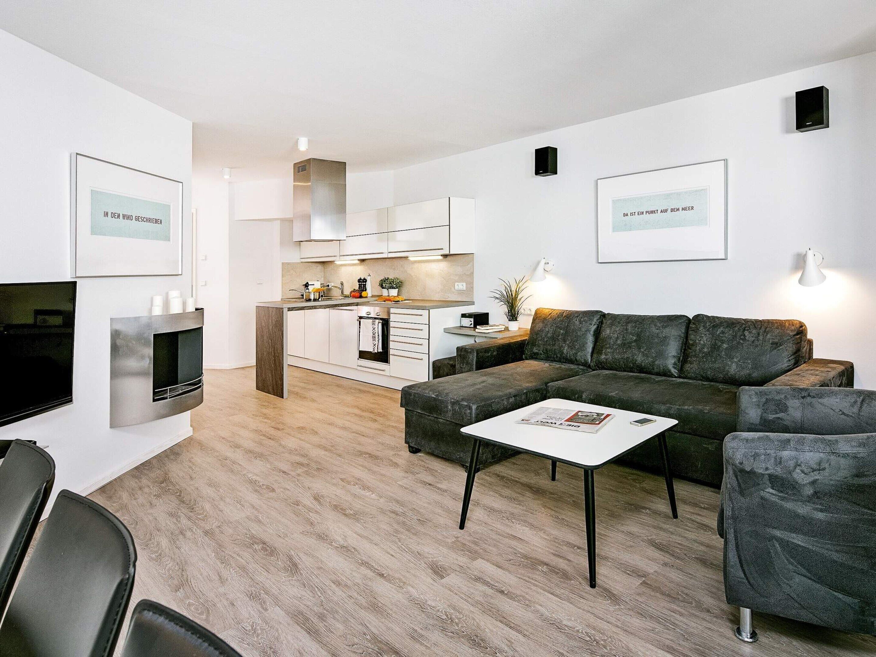 A modern living space with a sofa, coffee table, and a kitchen area in the background.