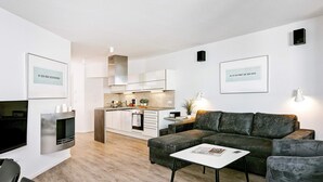 A modern living space with a sofa, coffee table, and a kitchen area in the background. - Holiday Home in Wendtorf (Wendtorf)