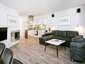 A modern living space with a sofa, coffee table, and a kitchen area in the background.