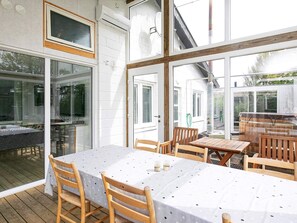 A covered outdoor dining area with a table and chairs, large windows, and a view of the surrounding area. - 4 Star Holiday Home in Vinderup (Vinderup)