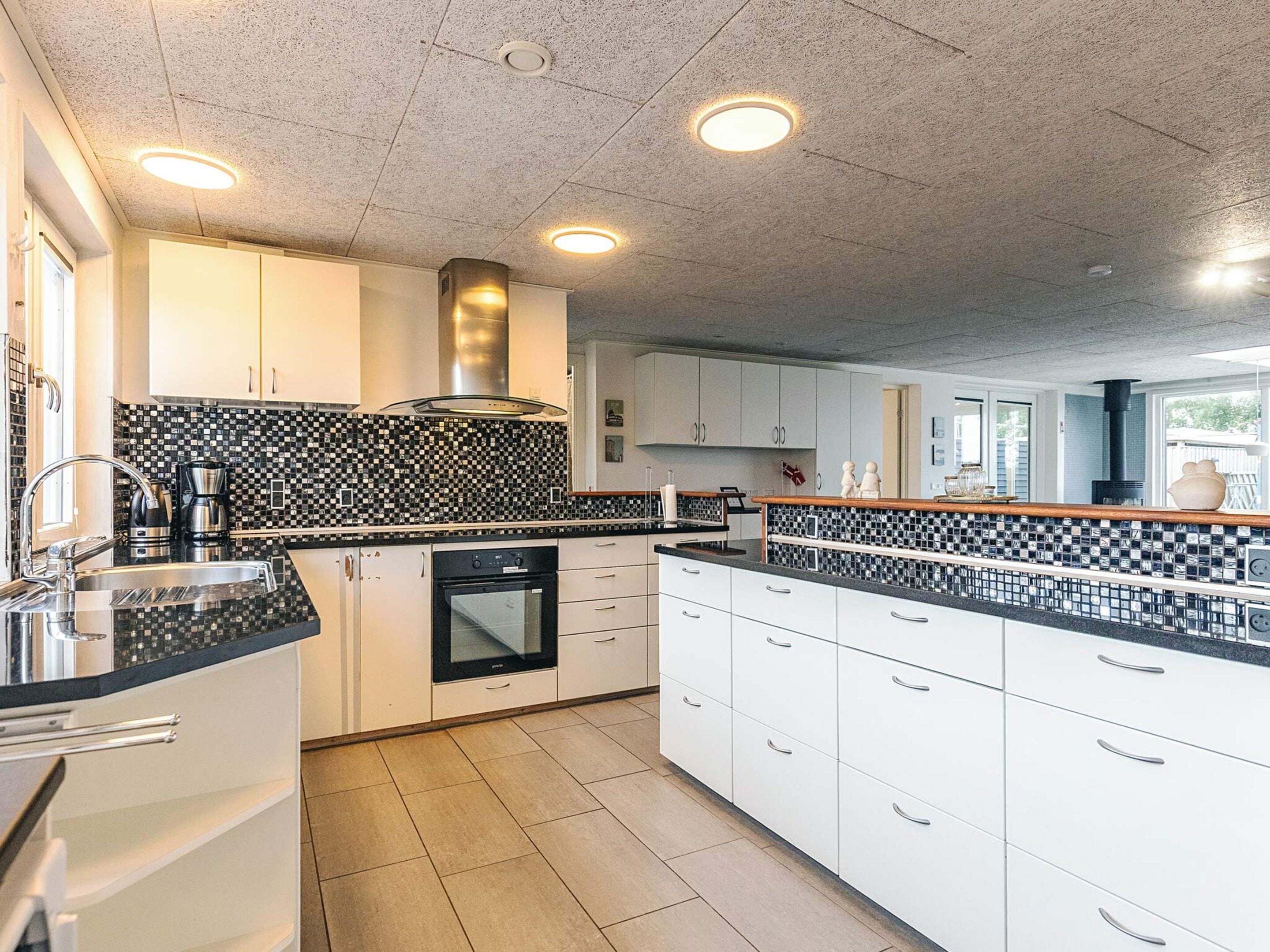 A modern kitchen with white cabinets, black and white checkered backsplash, and stainless steel appliances.