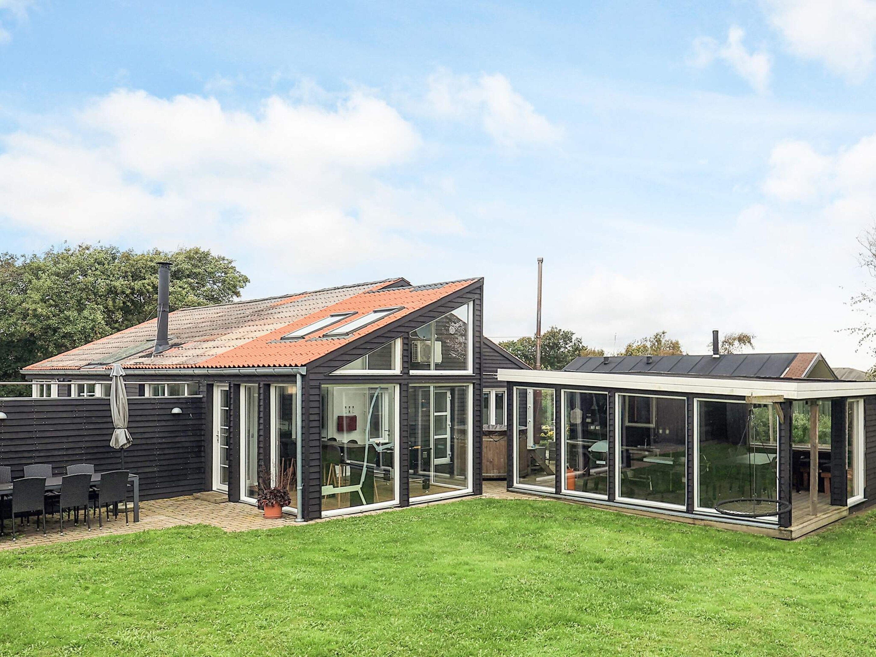 A modern house with a sloped roof, large glass windows, and a well-maintained lawn.