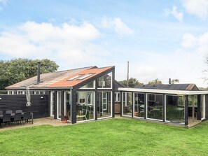 A modern house with a sloped roof, large glass windows, and a well-maintained lawn. - 4 Star Holiday Home in Vinderup (Vinderup)