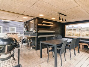 A modern kitchen with a built-in grill, dining area with chairs, and a large window. - 4 Star Holiday Home in Vinderup (Vinderup)