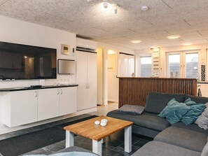 Een moderne keuken met witte kasten, een flatscreen televisie en een inbouwoven.