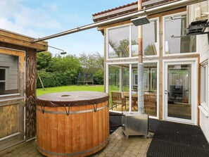 A wooden hot tub with a metal frame, a glass door leading to a patio, and a metal heater.