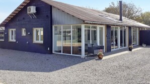 A modern house with a large glass extension, a gravel driveway, and a chimney. - 4 Star Holiday Home in Vinderup (Vinderup)