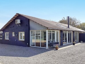 A modern house with a large glass extension, a gravel driveway, and a chimney. - 4 Star Holiday Home in Vinderup (Vinderup)