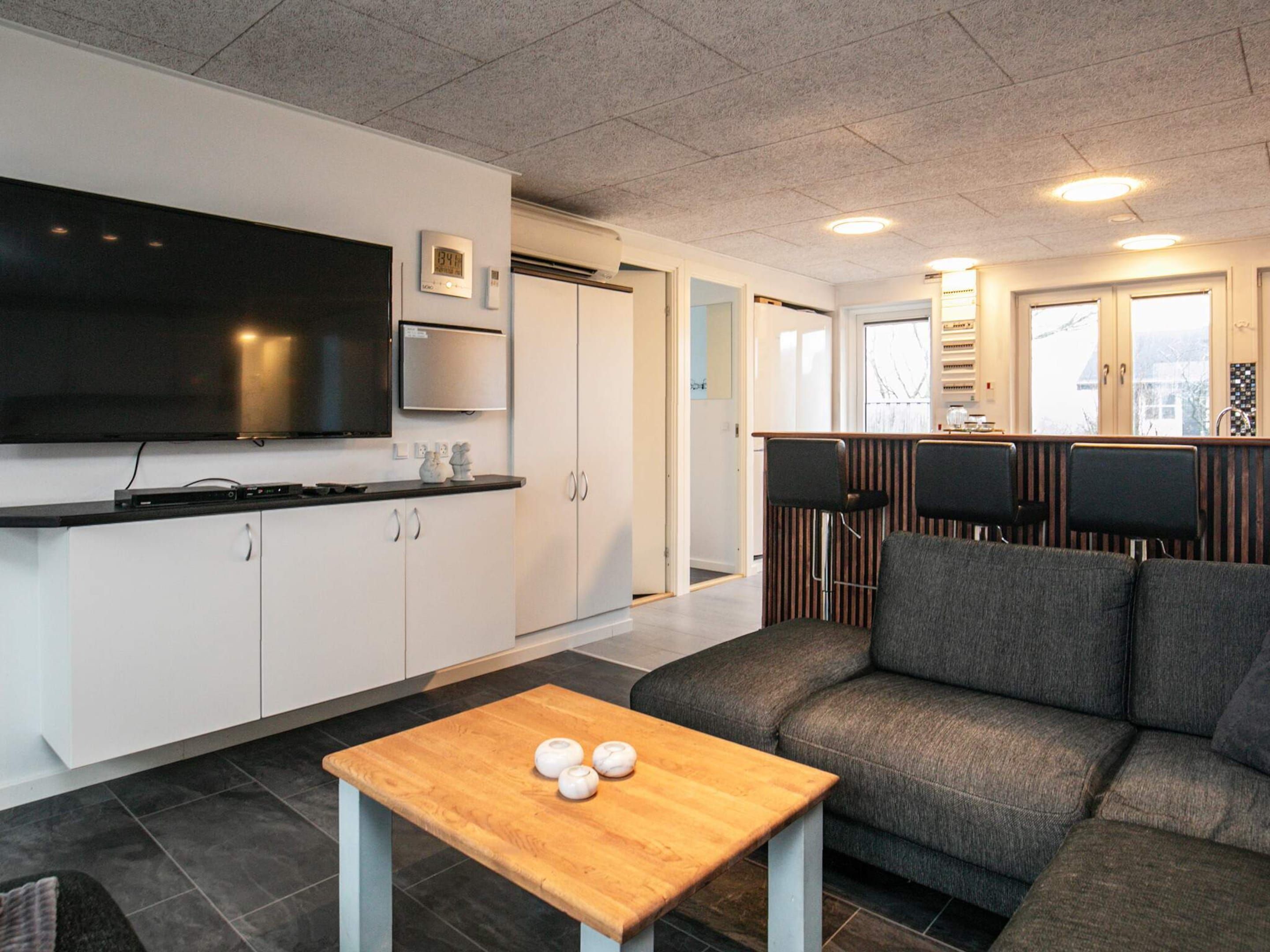 A modern living room with a sofa, a wooden coffee table, and a television.