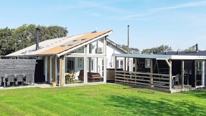 A modern house with a large glass extension, a covered patio, and a well-maintained lawn. - 4 Star Holiday Home in Vinderup (Vinderup)