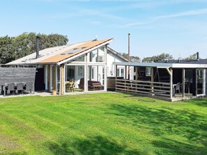 A modern house with a large glass extension, a covered patio, and a well-maintained lawn. - 4 Star Holiday Home in Vinderup (Vinderup)