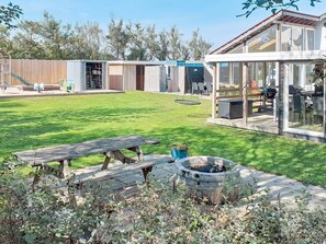 Una casa moderna con una amplia terraza, un brasero y una mesa de picnic.