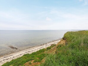 Un paisaje costero con una playa de arena y acantilados cubiertos de hierba.