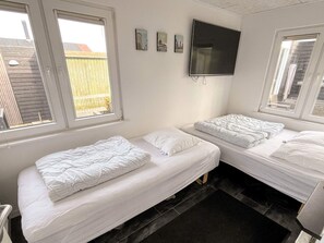 A room with two beds, a TV mounted on the wall, and a window. - 4 Star Holiday Home in Vinderup (Vinderup)