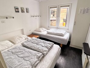 A small, clean room with two beds, a window, and a wooden nightstand. - 4 Star Holiday Home in Vinderup (Vinderup)