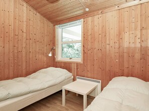 A room with wooden walls, a window with a view, a single bed, a small table, and a bedside lamp. - 6 Person Holiday Home in Jerup (Jerup)