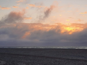 A beach with a view of the ocean and clouds in the sky.