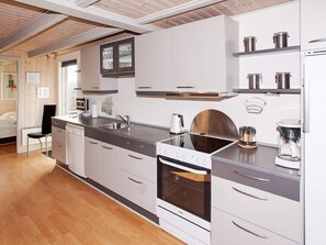 Una cocina moderna con armarios blancos, horno empotrado y cafetera.