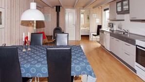 Una habitación acogedora y bien iluminada con una mesa de comedor, sillas, chimenea y una zona de cocina.