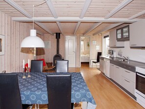 Una habitación acogedora y bien iluminada con una mesa de comedor, sillas, chimenea y una zona de cocina.