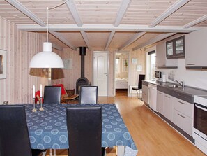 A cozy, well-lit room with a dining table, chairs, a fireplace, and a kitchen area. - Quaint Holiday Home in Hemmet near Fjord (Hemmet)