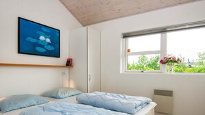 A bedroom with a bed, a window, a radiator, a shelf with a book, and a painting on the wall. - 8 Person Holiday Home in Brovst (Brovst)