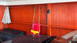 Een kamer met houten lambrisering, een rode stoel, een zwarte bank en een witte paraplu.
