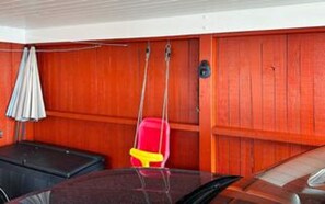 A room with wooden paneling, a red chair, a black bench, and a white umbrella.