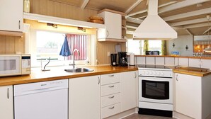 A compact kitchen with white cabinetry, a built-in microwave, a stove, and a sink. - 4 Star Holiday Home in Sjolund (Sjølund)