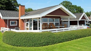 Een tweelaags huis met een overdekte veranda, een bakstenen schoorsteen en een witte hek.
