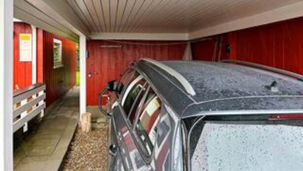 Een auto geparkeerd in een gebouw met een rode buitenkant en een wit plafond.