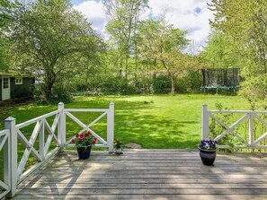 A wooden deck with white railings, a grassy yard, and a house in the background. - 5 Person Holiday Home in Vejby (Vejby)
