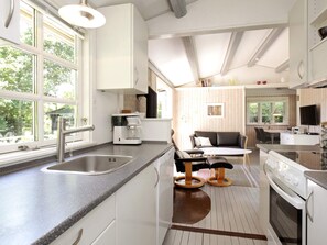 A modern kitchen with a large window, a coffee maker, a stove, and a dining area with a sofa and table.