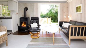 A cozy living room with a fireplace, a black leather chair, a wooden sofa, and a dining table. - 5 Person Holiday Home in Vejby (Vejby)