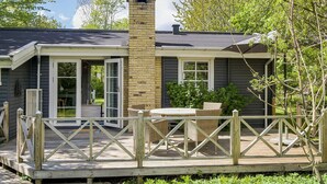 A house with a deck, a chimney, and a door leading to a covered patio. - 5 Person Holiday Home in Vejby (Vejby)