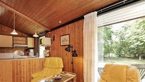 Een gezellig cabin interieur met houten wanden, een eethoek en een groot raam met uitzicht op de omgeving.