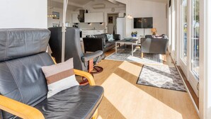 Un salon moderne avec un canapé, des fauteuils, une table basse et un téléviseur.