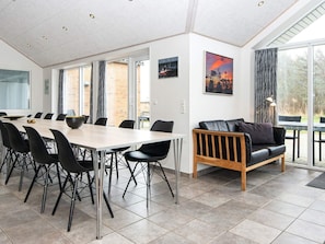 Et moderne spiseområde med et langt bord, sorte stole og en lædersofa.