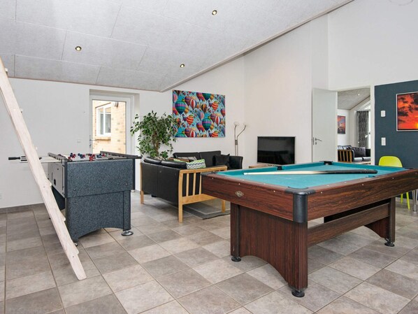 A recreational room with a pool table, foosball table, and a sofa.